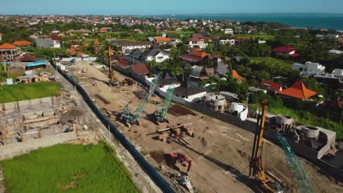 一架无人机飞越高高的建筑起重机的视频，在地面上建造了一座新建筑