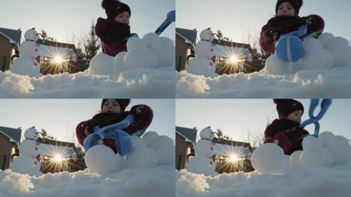 可爱的小女孩在一个有趣的雪人附近打雪球