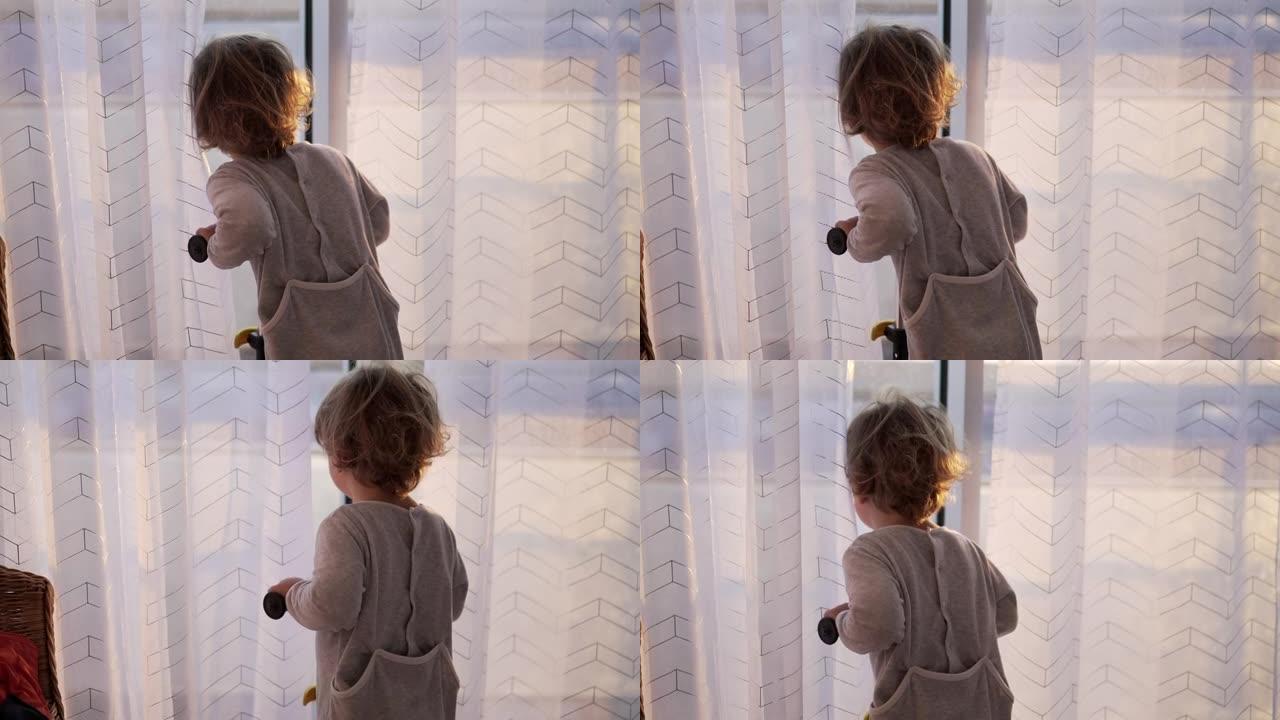 婴儿蹒跚学步的孩子站在窗前看着早晨