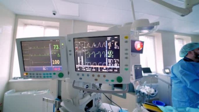 显示心脏参数的医疗屏幕。一群医生正在后台进行手术。手术期间用生命体征显示。视频。