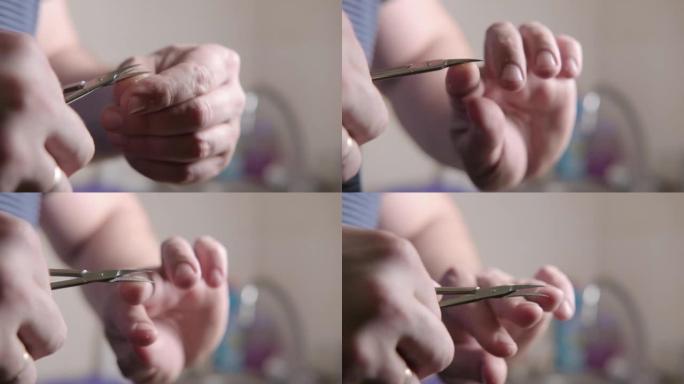 一名男子用剪刀在他的手上剪指甲特写。