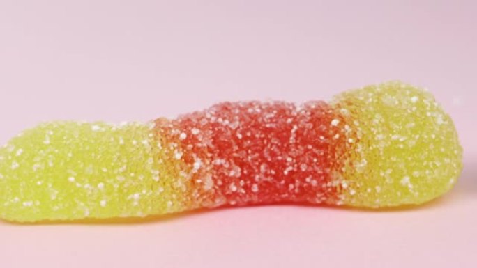 蠕虫形状的软糖糖果。粉色背景，宏观高质量4k镜头