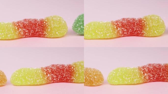 蠕虫形状的软糖糖果。粉色背景，宏观高质量4k镜头