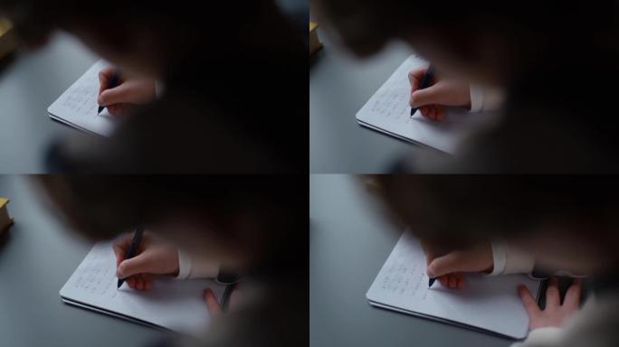 小学生男孩的特写手在纸上写笔记本解决数学方程式坐在家里的桌子上