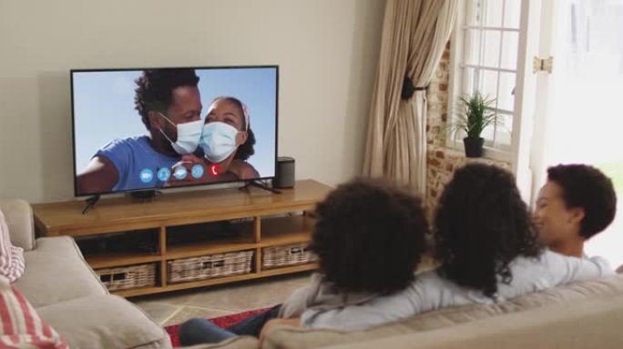坐在家里沙发上的非裔美国人家庭在电视上进行视频通话的后视图