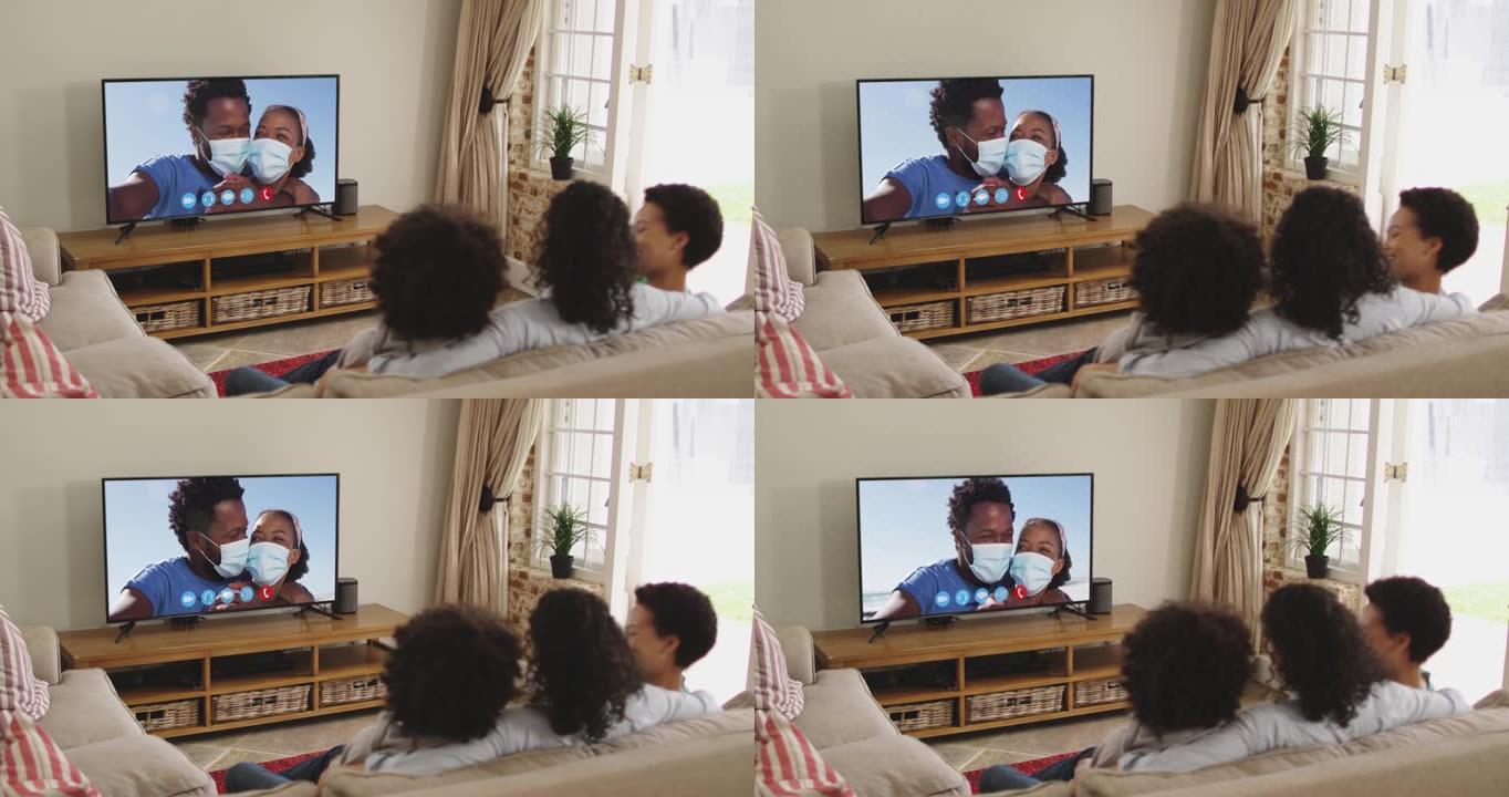 坐在家里沙发上的非裔美国人家庭在电视上进行视频通话的后视图