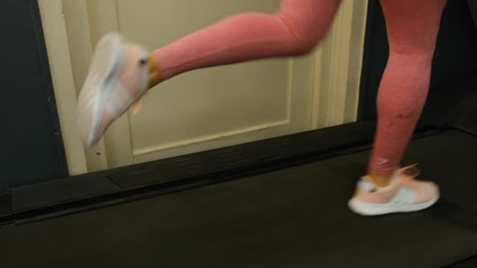 在健身房的跑步机上奔跑的无法识别的女运动员的特写镜头