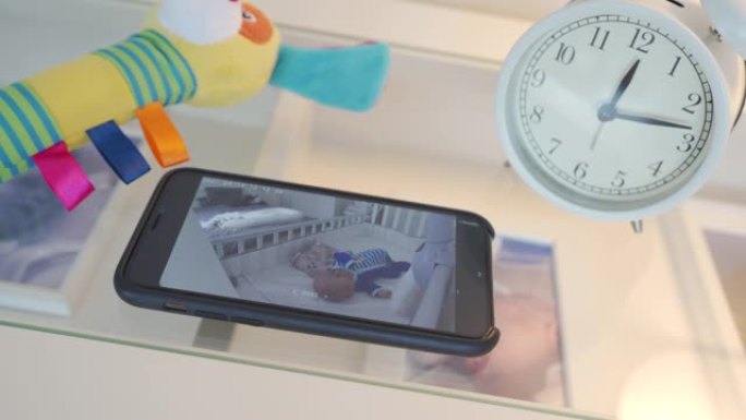 手机上的视频婴儿监视器应用程序，智能手机屏幕上的新生儿睡在婴儿床里