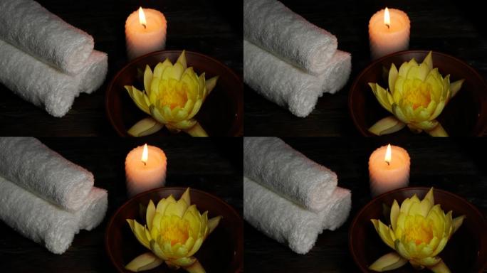 木桌上的黄莲睡莲花、毛巾和蜡烛