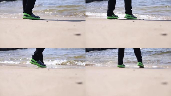 脚穿着胶鞋跑过海浪的海洋或海沙海岸海浪袭击海岸，旅行陌生的地方积极情绪度假上衣