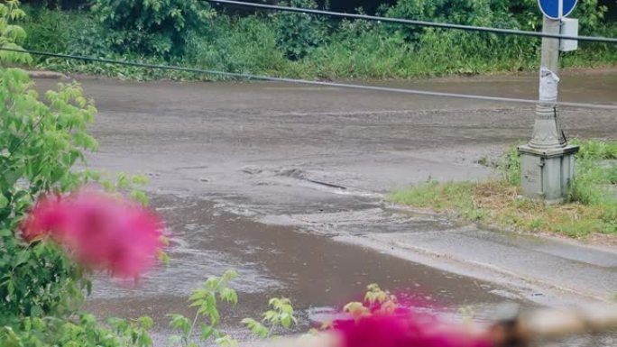 下雨天，肮脏的水流沿着河对面的道路流动。下水道系统无法承受倾盆大雨