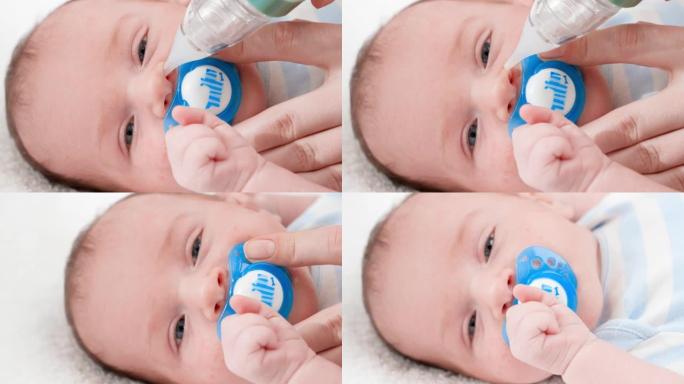 母亲用吸鼻器清洁鼻子并取出粘液时，婴儿躺在婴儿床中的小婴儿的特写镜头。婴儿和新生儿卫生保健的概念。有