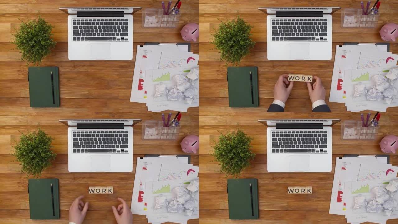 文字作品由木制立方体制成，用手放在办公室的桌子上，放在文件和笔记本电脑之间。概念办公室工作