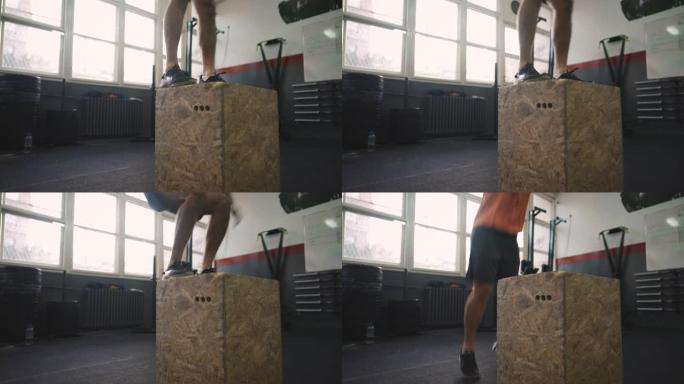 无法识别的运动型男子在健身房的盒子上跳跃