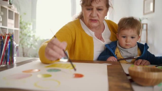 祖母和她的小孙子在家里一起画画
