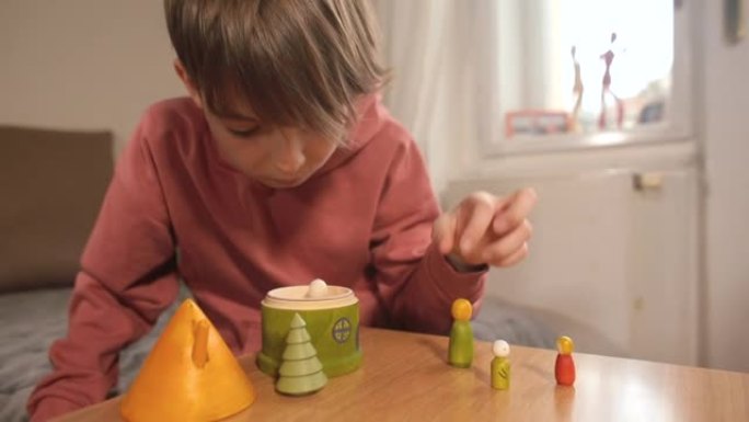 一位才华横溢的少年将木制人物组合在一起。家里的环保玩具。