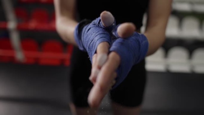 女人在拳击台上用拳击胶带包裹的手上撒粉