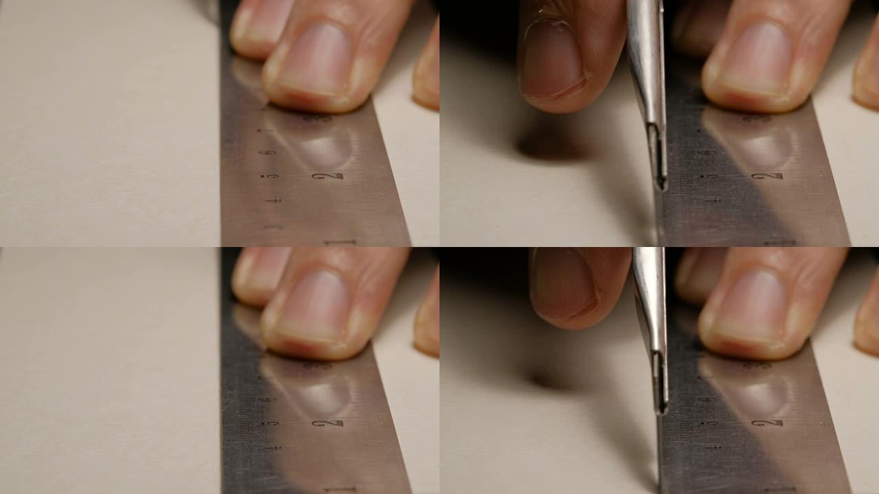 男性建筑师用切割刀和金属尺切割白色纸板的特写镜头。模型制作过程。
