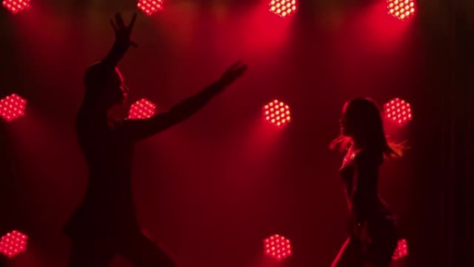 帕索多布、伦巴、桑巴、恰恰恰舞。双人舞者表演的拉丁美洲舞蹈元素。黑暗工作室中红色灯光背景下的男人和女