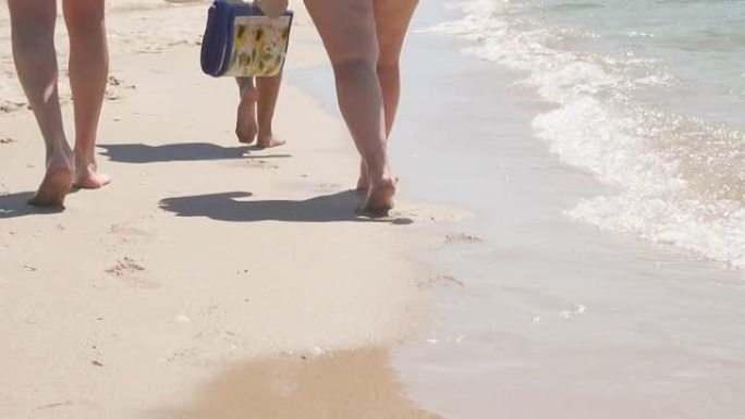 双脚赤脚在海浪沙滩上行走的特写镜头。男人和女人的脚在阳光明媚的日子沿着海滩散步