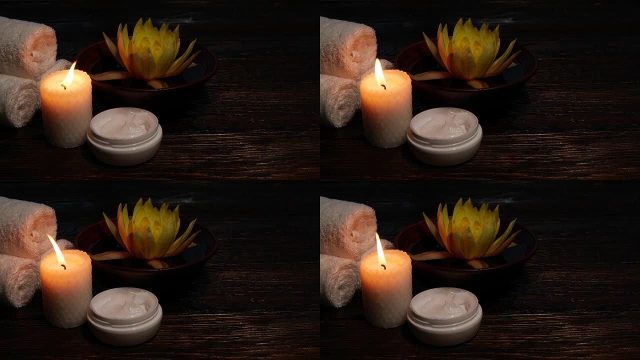 木桌上的莲花睡莲花、奶油、毛巾和蜡烛