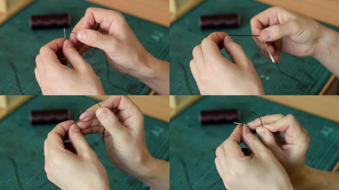 tanner的手将线拉入针中并打结的特写。手工皮革制品的生产。爱好概念