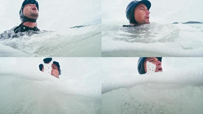 冲浪摄影师。戴着保护帽的年轻人从海沫中出现，深呼吸