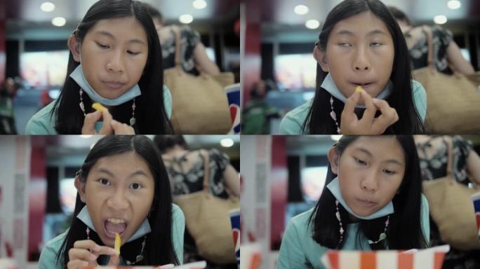 快乐的亚洲女孩在垃圾食品餐厅吃法式油炸与家庭，生活方式的概念。