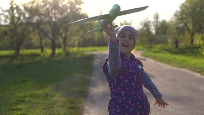 户外手握玩具飞机的小女孩，橡胶马达的螺旋风棒