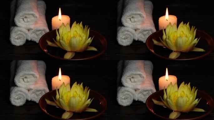 木桌上的黄莲睡莲花、毛巾和蜡烛