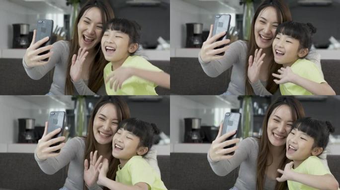 快乐的年轻亚洲妈妈和女儿用智能手机挥手和家人打招呼打视频电话。