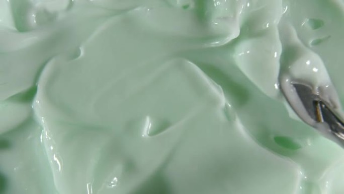 液体乳霜的运动，绿色的化妆品质地与旋转。轮廓，弥补背景。美容护肤产品样品。慢动作。顶视图。4K超高清