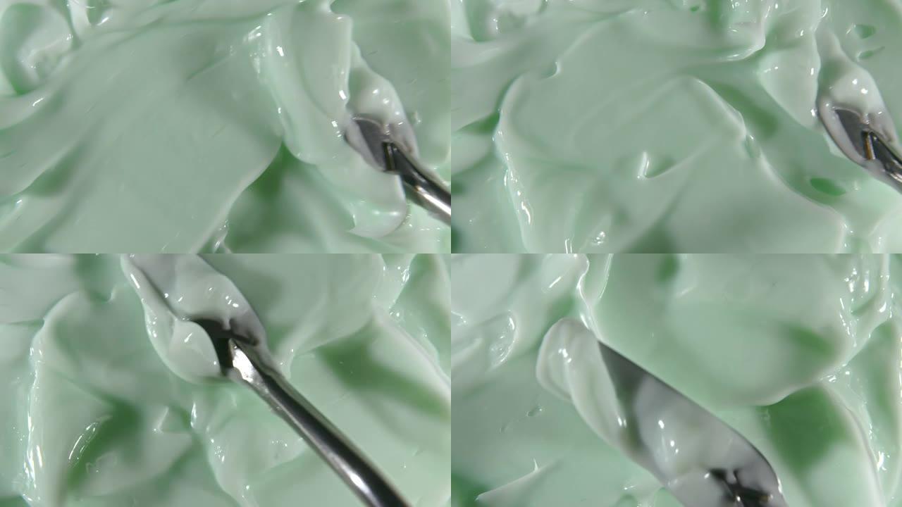 液体乳霜的运动，绿色的化妆品质地与旋转。轮廓，弥补背景。美容护肤产品样品。慢动作。顶视图。4K超高清