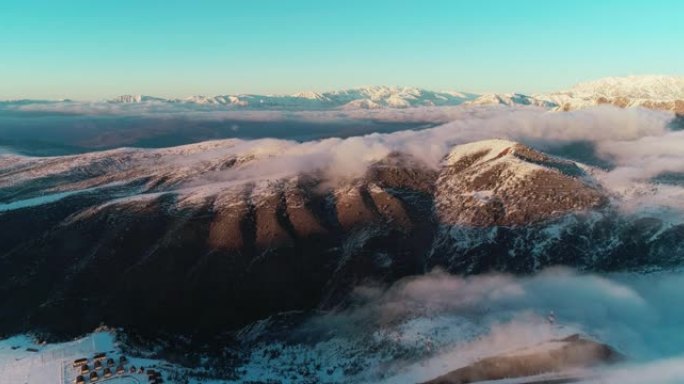 无人机摄像机在日落时穿越中亚雪山上空的云层拍摄