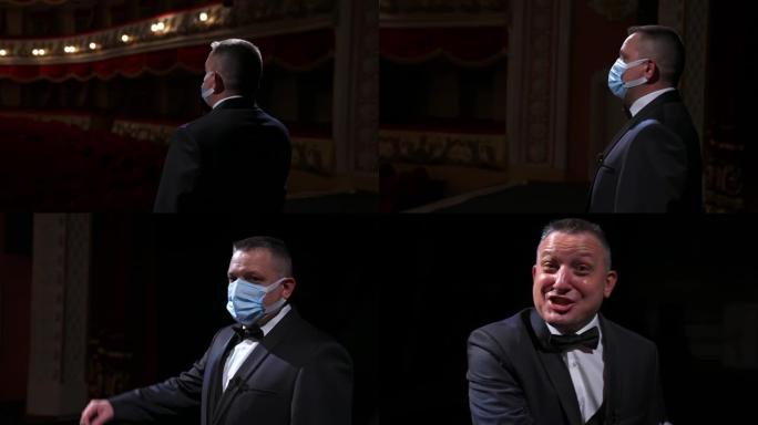 剧院演员戴着医用面具在舞台上讲话。穿着西装的播音员站在空荡荡的剧院大厅前。大流行概念。