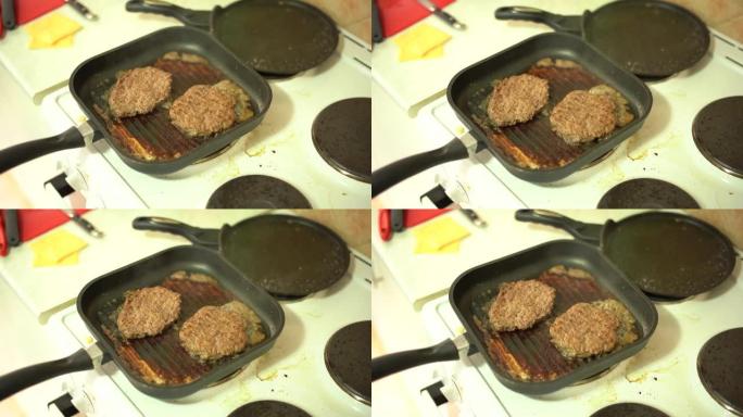 汉堡肉饼在炉子上的烤盘中油炸。