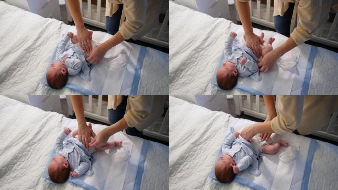 年轻的有爱心的母亲在晚上更换刚出生的男婴的尿布的俯视图。卫生、母亲和儿童健康的概念