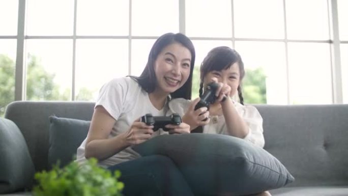 年轻的母女和客厅沙发上的控制器一起玩电子游戏