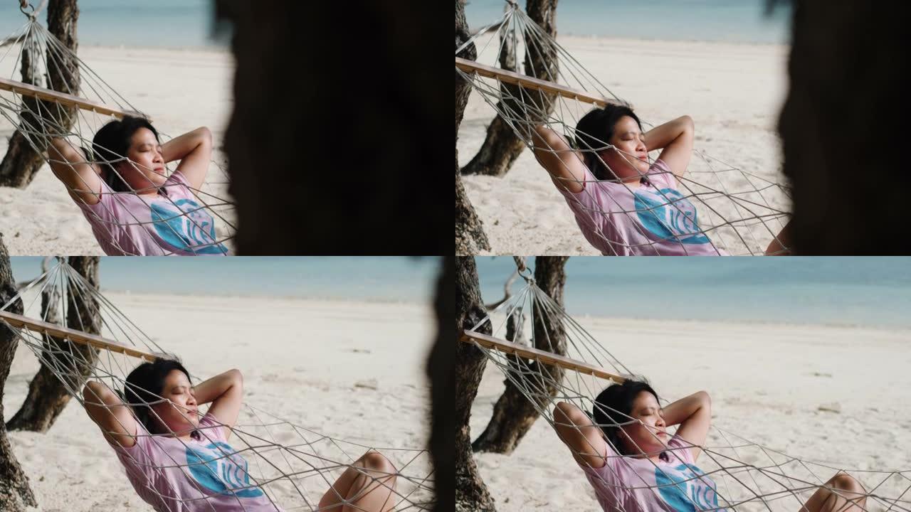 暑假在海滩的吊床上休息和睡觉的亚洲妇女