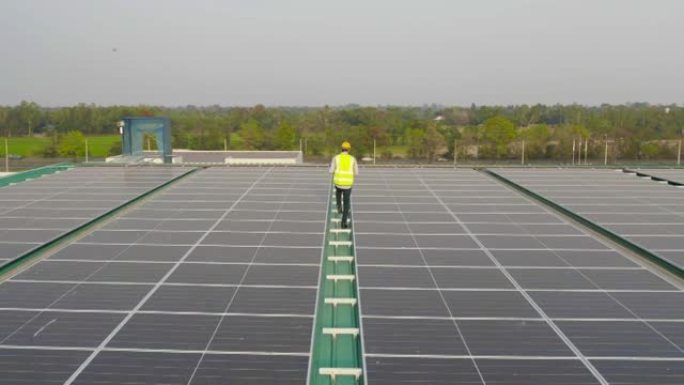 在工厂工业中，屋顶上有太阳能电池板或太阳能电池的工程师或工人，人的空中俯视图。发电厂，可再生能源。电