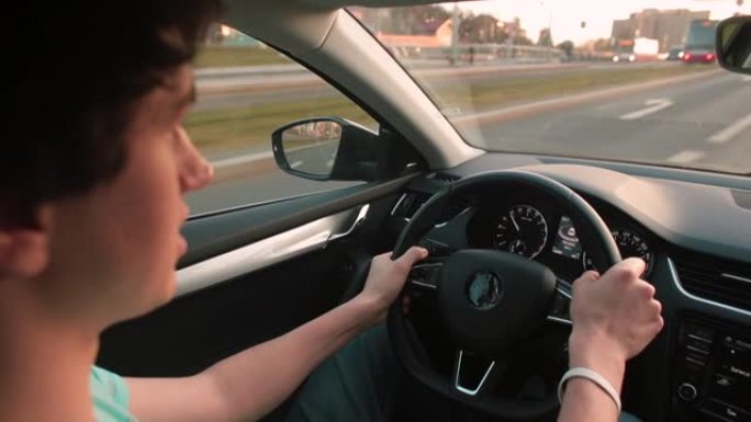 男性驾驶汽车，用手握方向盘。合规速度限制。