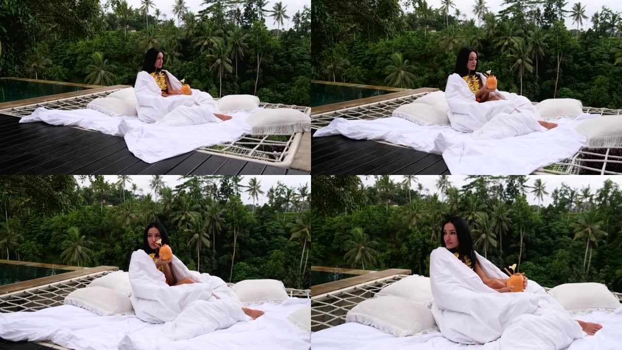 女孩在吊床，白色亚麻布和椰子中放松。背景雨林