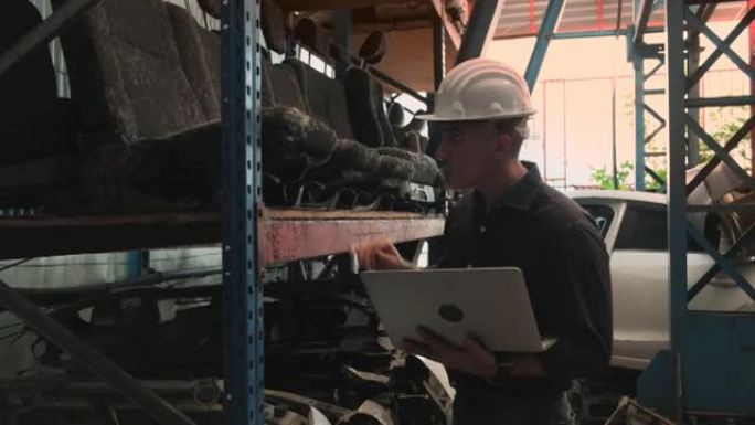 高加索男性工程师: 一家汽车备件仓库工厂的所有者，检查汽车座垫库存。使用笔记本电脑查看工业生产中的订
