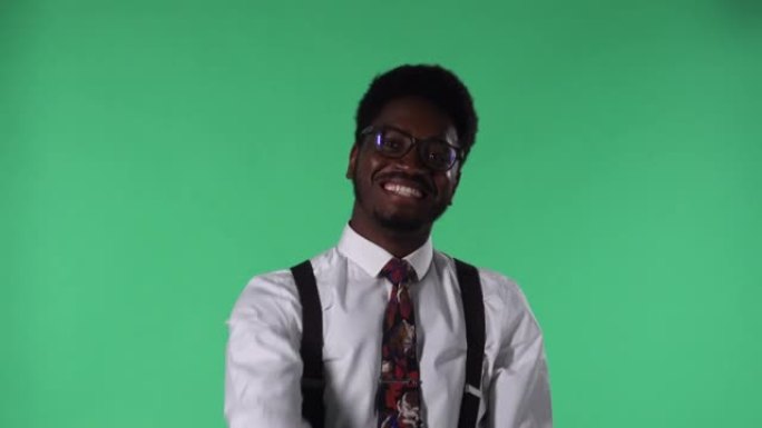 年轻的非洲裔美国人微笑的肖像，讲述一些有趣的事情，并指向对话者。黑色男性，领带和白色衬衫眼镜，在工作