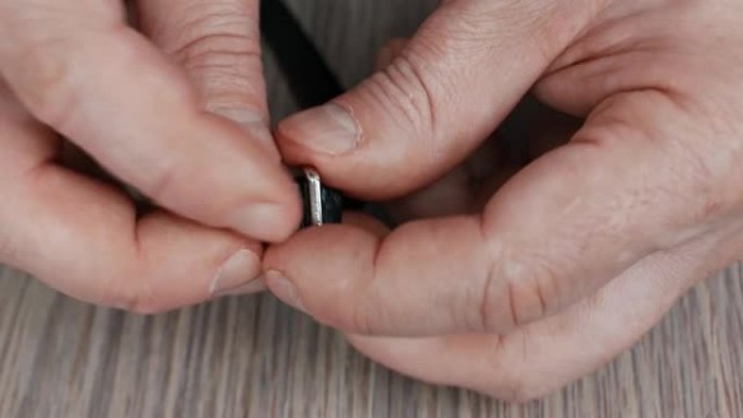 皮革工人将紧固件放在皮革手镯上并进行演示。手工制作的皮革配件。