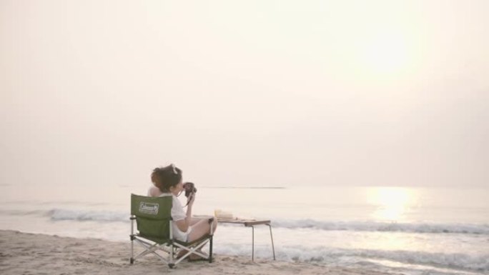 年轻女子坐在沙滩上看海浪。