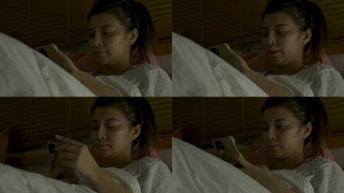 亚洲妇女在床上看电视和使用moblie的特写镜头。