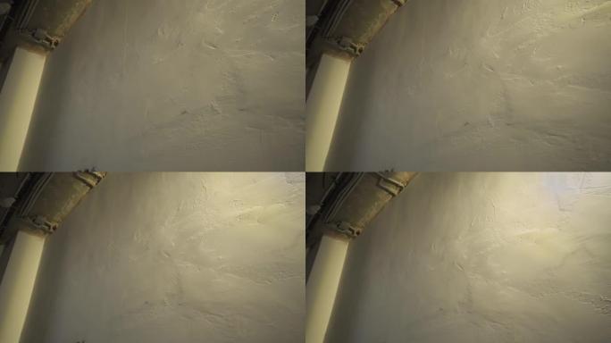 抹灰墙专用灯照亮的不平坦抹灰墙。面对工作不正确完成的缺陷。凌乱的墙面灰泥纹理