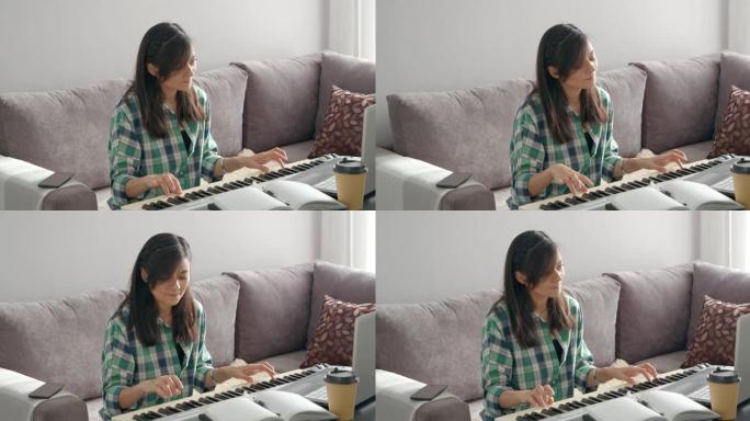 年轻的音乐老师在家工作时，使用笔记本电脑远程在线弹奏电子钢琴教学笔记。