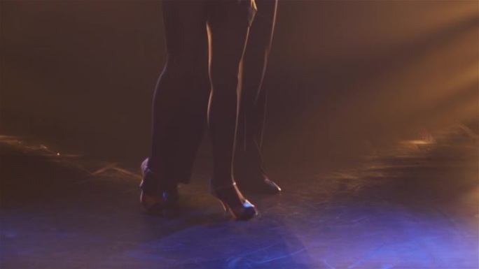 一对专业舞厅舞者表演的性感伦巴舞。一个男人和一个女人在烟雾和黄光的黑暗工作室里与他们的身体挤在一起跳